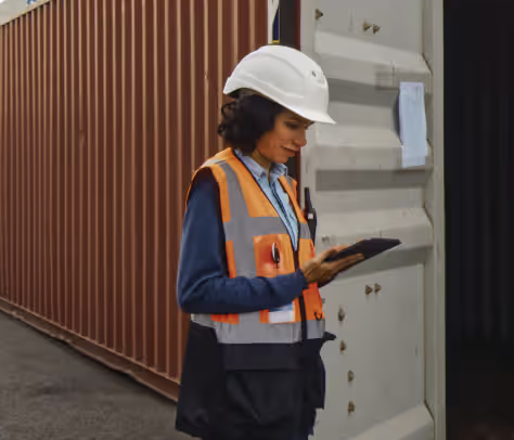 Field supervisor inspecting on tablet at site with containers