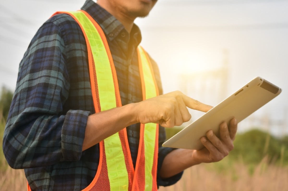 Field worker reporting on tablet in hi-vis vest