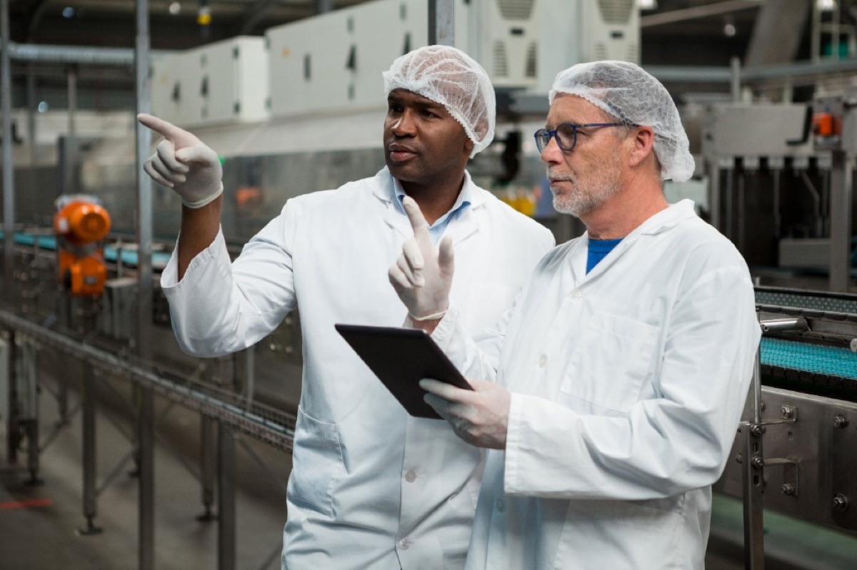 Worker with tablet in factory with conveyor