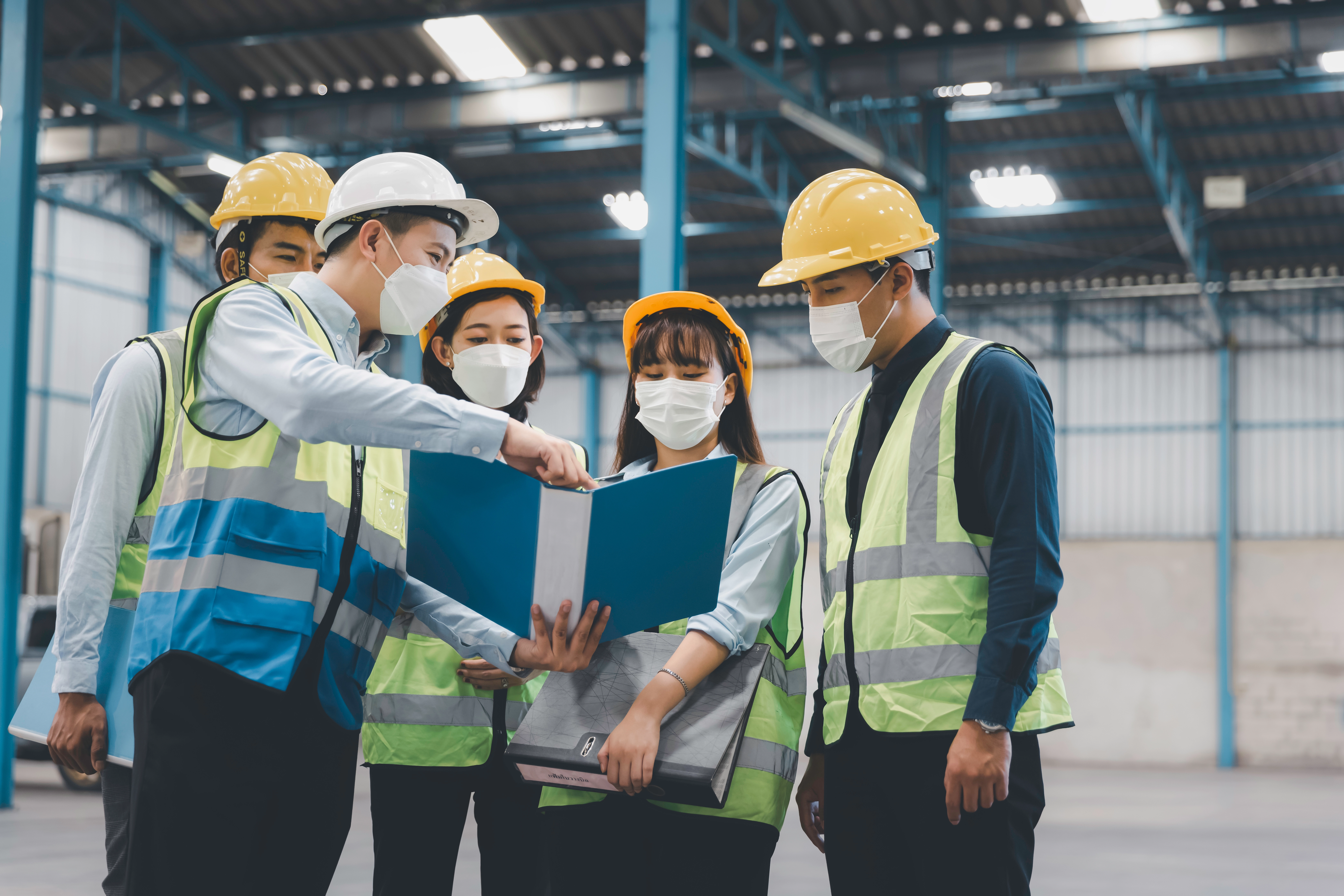 Factory team in masks holding a workplace safety meeting