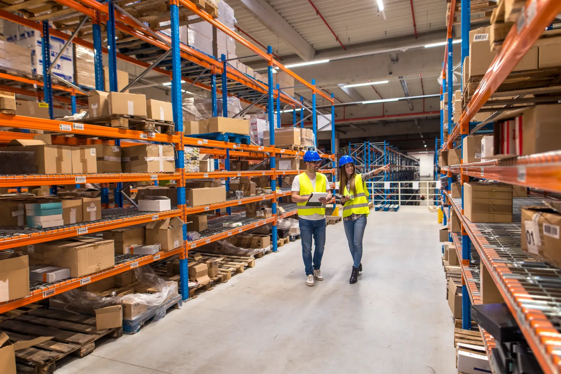 Two warehouse workers walking through a distribution storage area